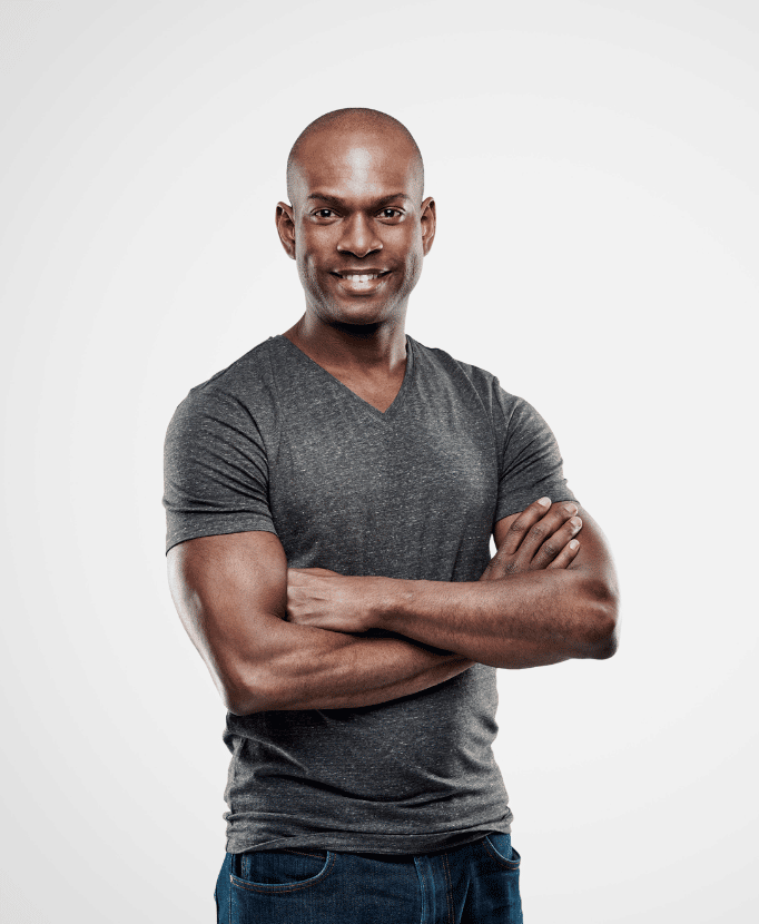 Attractive, muscular black man stands with his arms crossed modeling his shaved head to show the benefits of scalp micropigmentation and other conceal services on the homepage.