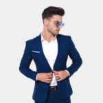 attractive dude standing in a toxido suit and wearing shade