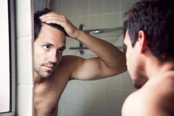 A man looking at the mirror examining his hair.